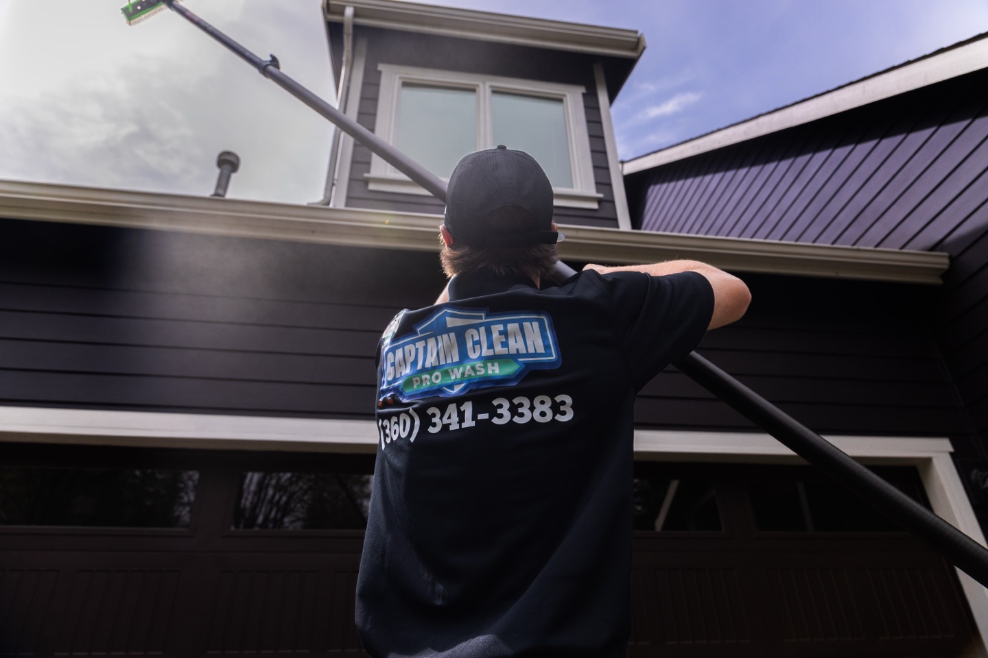 Technician washing the second story with a long brush pole