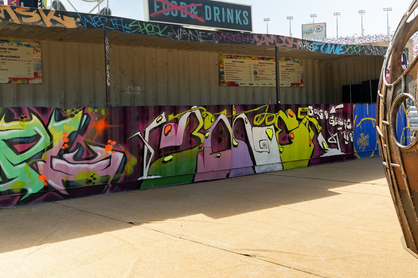 Painted lettering along a container wall below the Food & Drinks bar
