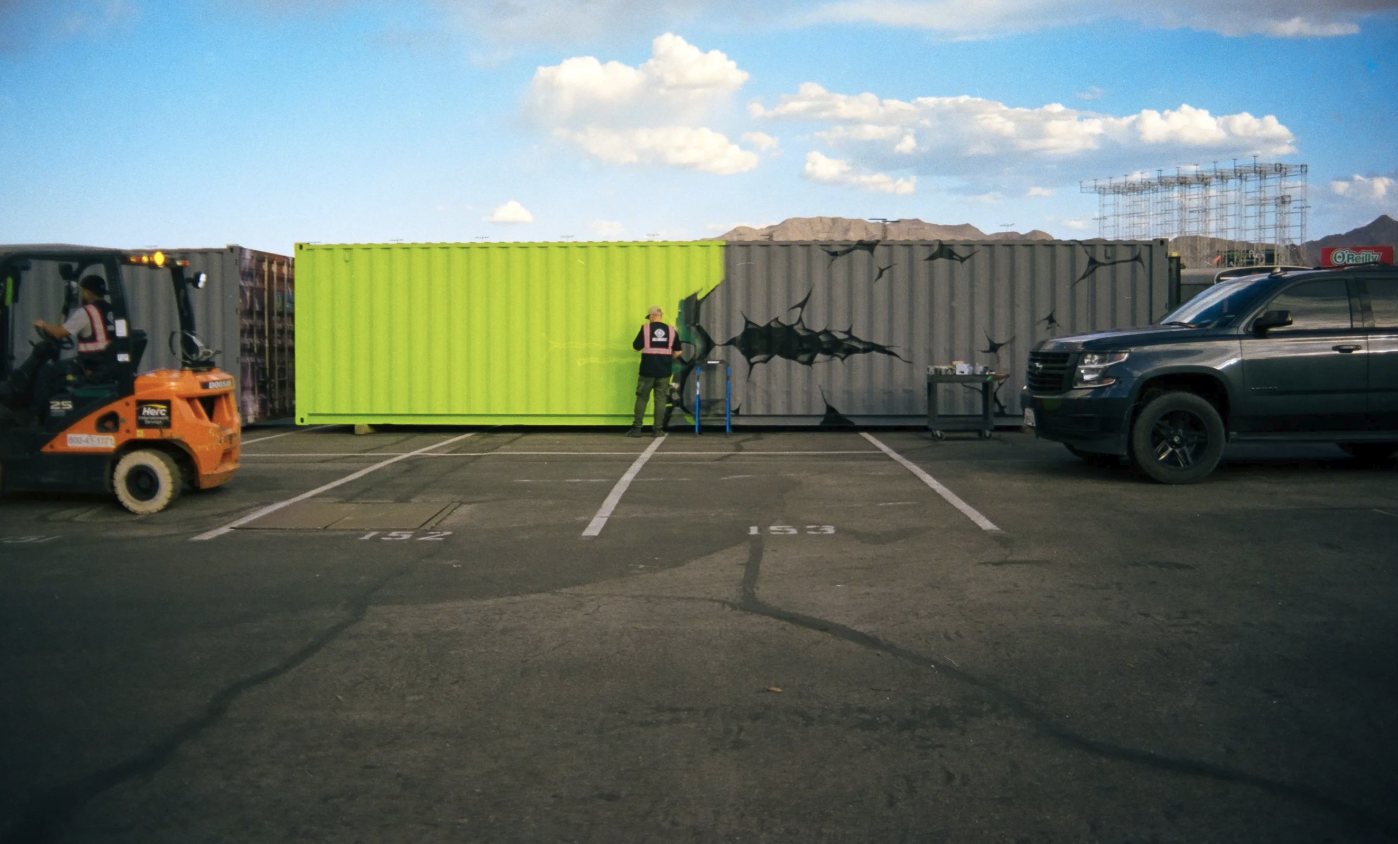 Muralist painting a shipping container at EDC Las Vegas, shot on film