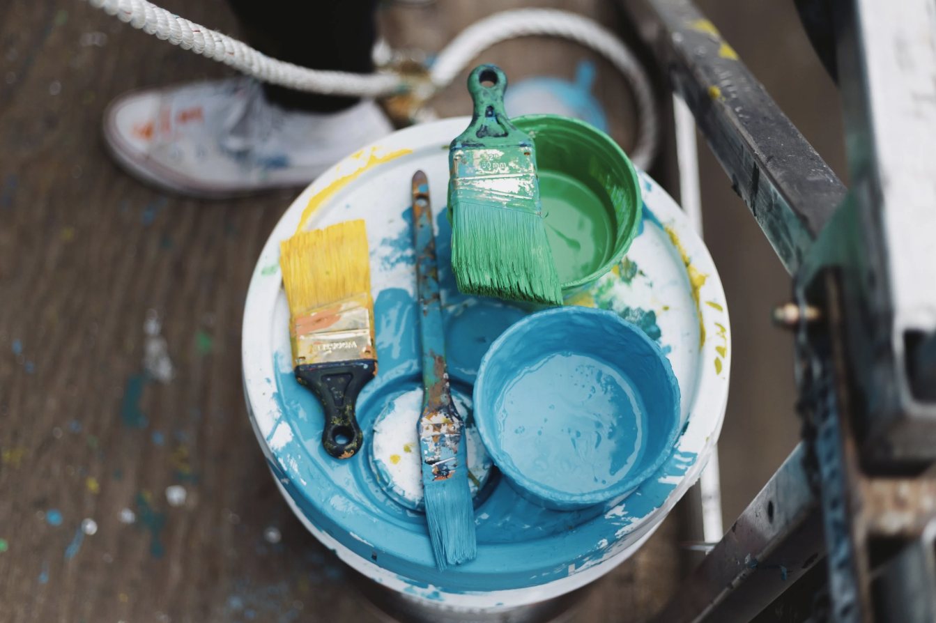 Brushes and mixed paint on the lid of a bucket